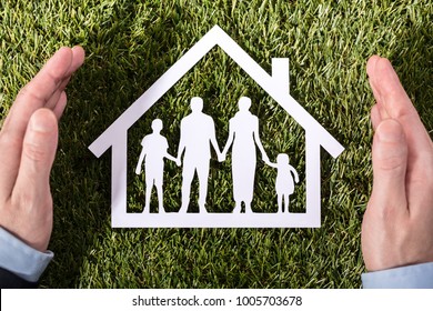 High Angle View Of A Person's Hand Holding Family Home On Green Grass - Powered by Shutterstock