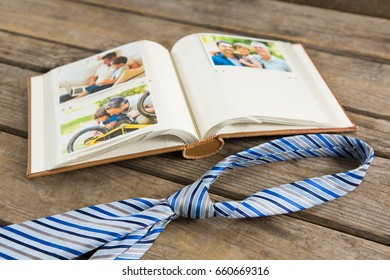 High angle view of photo album by necktie on wooden table - Powered by Shutterstock