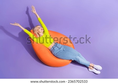 High angle view photo of cheerful lovely stylish girl relaxing comfortable bag empty space isolated on purple color background