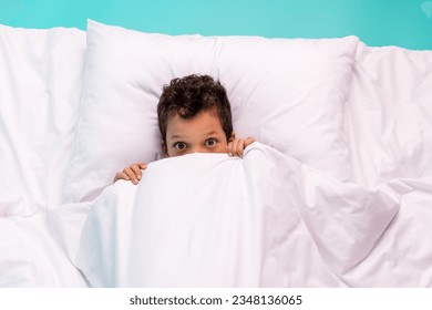 High angle view photo of frightened small boy lay bed pillow cover face blanket peeking look isolated on teal color background - Powered by Shutterstock