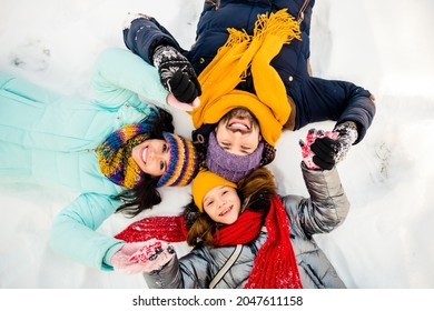 High Angle View Photo Of Happy Excited Cheerful Family Lying On Ground Snow Having Fun Winter Holiday Vacation