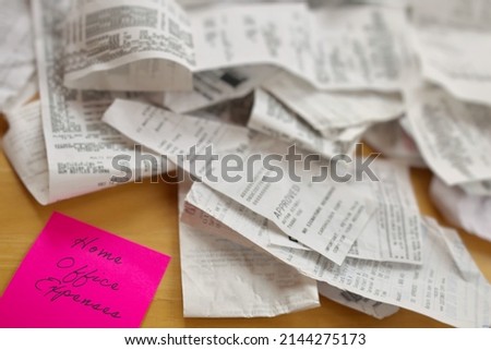 High Angle View of Pile of Receipts with Home Office Expenses Pink Sticky Note on Table