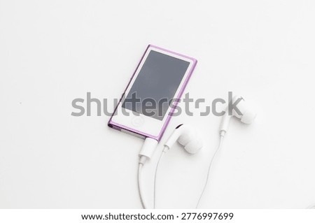 High angle view of pink MP4 Player with white wired earbuds on white background
