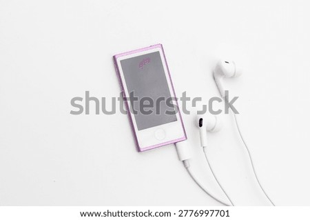 High angle view of pink MP4 Player with white wired earbuds on white background