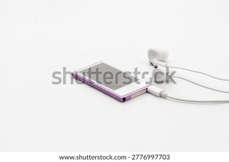 High angle view of pink MP4 Player with white wired earbuds on white background