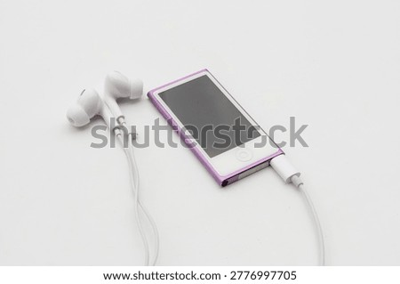 High angle view of pink MP4 Player with white wired earbuds on white background