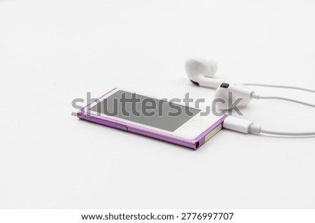 High angle view of pink MP4 Player with white wired earbuds on white background