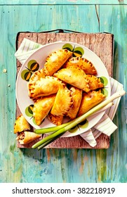 High Angle View Of Plateful Of Fresh Baked Empanada Pastries With Fresh Green Onions Served On Rustic Blue Painted Wooden Table