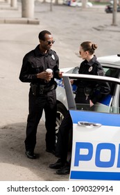 High Angle View Of Police Officers Drinking Coffee Near Police Car