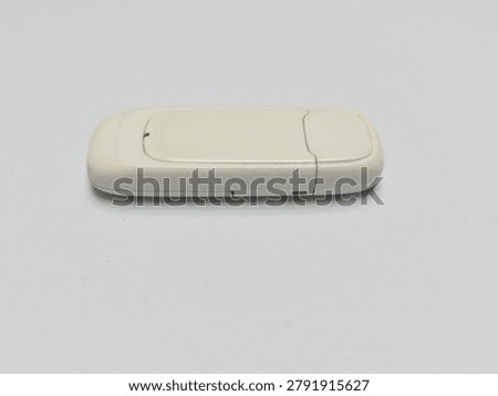 High angle view of portable cell broadband network dongle for computer digital connection on white backdrop.