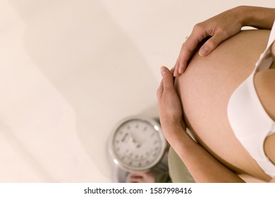 High angle view of pregnant woman standing on scale - Shutterstock ID 1587998416