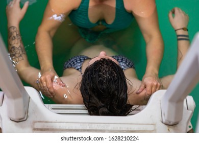 High angle view of pregnant woman leaning on swimming pool ladder while female experienced professional therapist giving massage on shoulder - Powered by Shutterstock