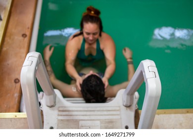 High angle view of pregnant woman leaning on swimming pool ladder while female experienced professional therapist giving massage - Powered by Shutterstock