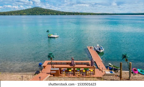 High Angle View Of A Private Lakefront Recreation Area, Including A Wooden Deck, Boat Dock, Boats, Kayaks, Seats, And Accessories. Green Lake, Central British Columbia, Canada.