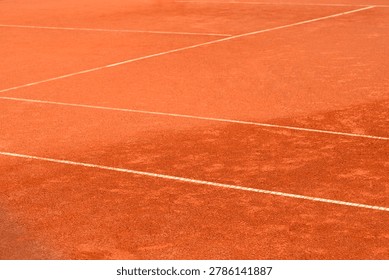 High angle view of a professional red clay tennis court showing textured orange dirt surface and crisp painted white boundary lines.