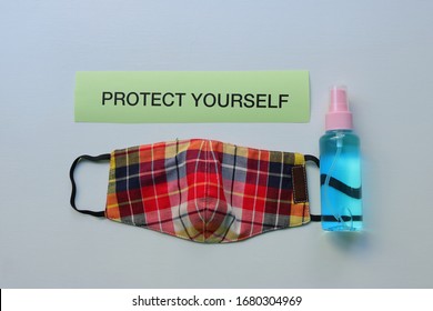 High Angle View Of Protect Yourself Sign, Handwash Gel And Face Mask Made From Washable Plaid Cloth On Wooden Surface, Safety Concept 