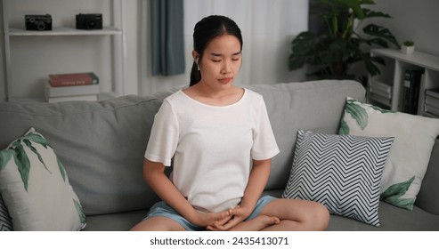 High angle view, Relaxed young woman wear wireless headphones enjoying rest on sofa in living room, breathing fresh air with eyes closed, meditating at home