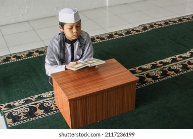 High angle view of a religious muslim child reading the Koran in the mosque