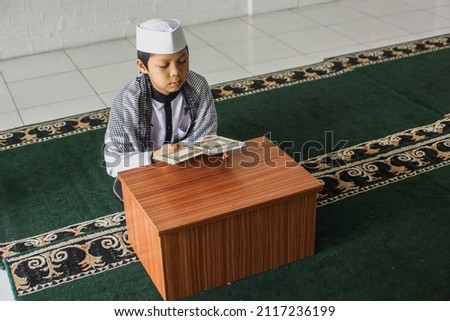 High angle view of a religious muslim child reading the Koran in the mosque