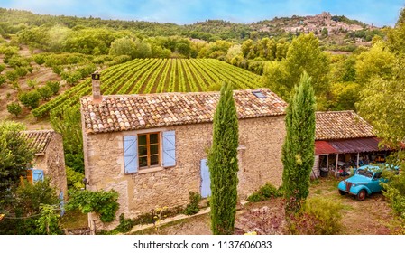 High Angle View From A Road Of A Traditional Old Stone Farm House And Picturesque Grape Vineyard, With Symmetrical Rows Of Vines In Provence, France.