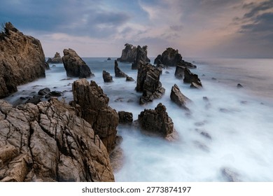 High angle view of Rock Formations and misty water at Gigi Hiu beach during sunset
