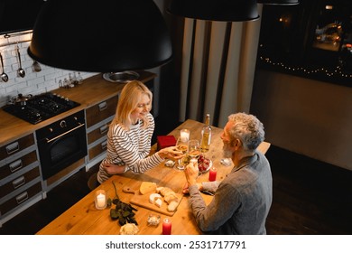 High angle view of romantic date of a married mature couple in the kitchen. Spouses, wife and husband, girlfriend and boyfriend celebrating with wine special event, anniversary, Valentine`s Day