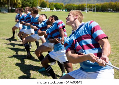 High angle view of rugby player pulling rope while standing on grassy field - Powered by Shutterstock