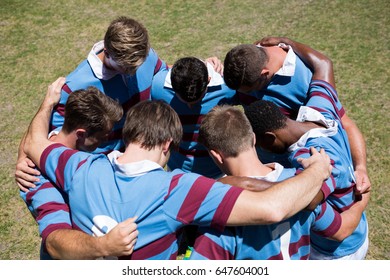 High Angle View Of Rugby Team Making  Huddle While Standing At Playing Field On Sunny Day 