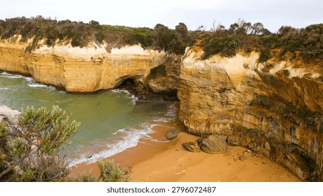 High angle view of rugged limestone cliffs surrounding a secluded sandy beach and cove.