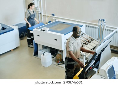 High angle view selective focus shot of African American man and Caucasian woman working in printing house preparing paper