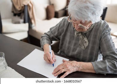 High Angle View Of A Senior Caucasian Woman Doing Alzheimer's Disease Cognitive Functions Clock Drawing Self Assessment Test At Home With Positive Results Suggesting Illness