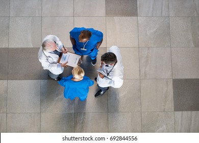 High Angle View Of Senior Doctors And Young Surgeons Discussing Over Patient Case. Doctors And Nurses Talking To Each Other About Medical Results  With Copy Space.