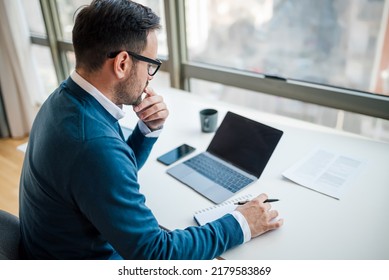 High Angle View Of Serious Businessman Writing Notes In Diary. Male Executive Is Using Laptop While Working At Desk. Black Blank Clean Empty Mock Up Template Background Computer Laptop Screen.