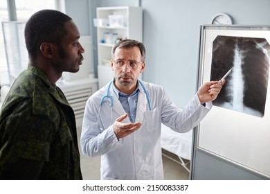 High Angle View Shot Of Doctor Wearing Lab Coat Showing Backbone X-ray Image To Military Patient And Speaking About Ways Of Treatment