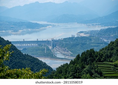 A high angle view shows the massive dam structure at the Three Gorges Reservoir near Yichang in China surrounded by green mountains and lush hills under a clear sky