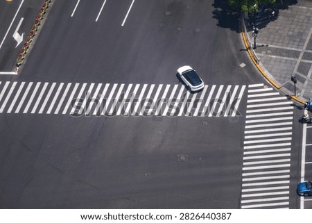 A high angle view of a signalised junction in a dense commercial district frames a motorcyclist filtering past stationary traffic. It shows how finite road space is shared each working day.