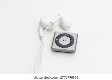 High angle view of silver Mp3 Player with white wired earbuds on white background
