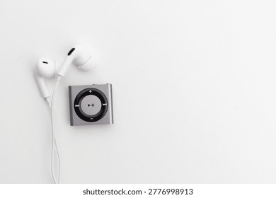 High angle view of silver Mp3 Player with white wired earbuds on white background