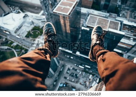 High angle view from skyscraper edge with feet overlooking cityscape, urban height and vertigo concept