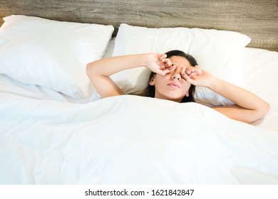 High Angle View Of A Sleepy Woman Rubbing Eyes While Lying In Bed At Home