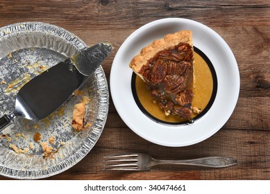 High Angle View Of A Slice Of Pecan Pie On A Plate Next To The Empty Tin With Server. On A Wood Table With Fork.
