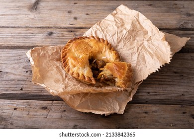 High angle view of sliced baked stuffed pie in brown wax paper on wooden table. unaltered, baked, sliced and healthy food concept.