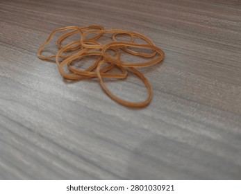 High angle view of small brown elastic rubber bands scattered on a wooden desk.