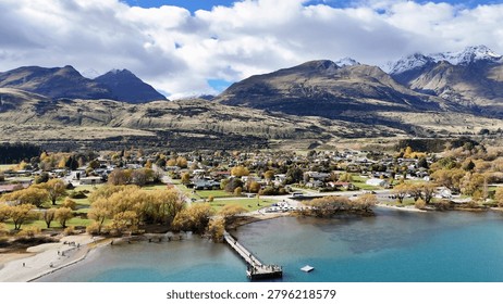 High angle view of a small lakeside town nestled beneath majestic snow-capped mountain peaks.