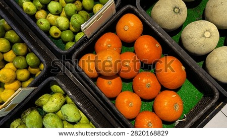 High Angle View of Small Orange Pumpkins, Melons, and Fruits in Market Baskets