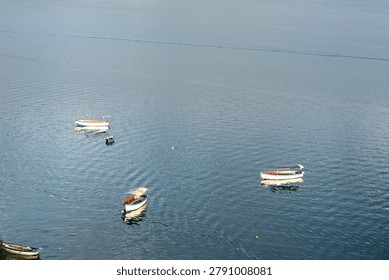 High angle view of small passenger boats floating on a vast blue lake surface.