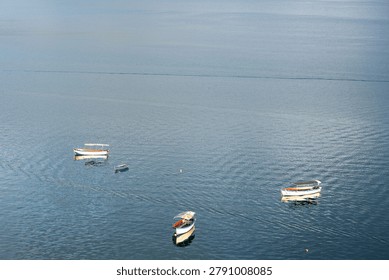 High angle view of small passenger boats floating on a vast blue lake surface.