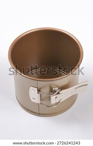 A high angle view of a small round bronze metallic springform cake pan with a silver latch mechanism shown on a neutral light grey background