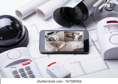 High Angle View Of Smart Home System On Mobilephone With Security Equipment And Blueprint