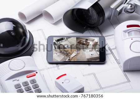 High Angle View Of Smart Home System On Mobilephone With Security Equipment And Blueprint